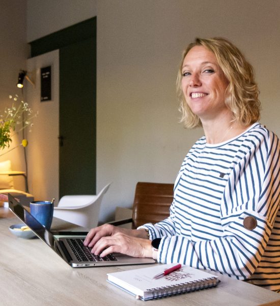 Vrouw met gestreepte trui achter laptop aan tafel Vrouw met gestreepte trui achter laptop aan tafel